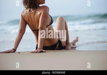 Closeup of woman sunbathing sitting on the sand beach. Stock Photo