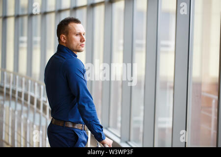Businessman standing near the window and looking into it. Stock Photo