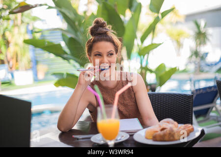 Young white student biting a pencil while doing his homework - Natural plants with a blurred background Stock Photo