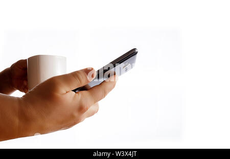 Hands holding mobile phone and coffee cup. Middle age woman using smartphone. White bacground. Stock Photo
