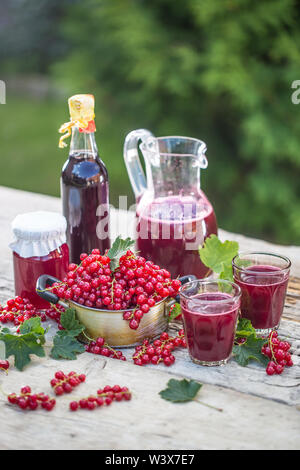 A selection of redcurrant products - marmalade jam syrup must and red vine on table in garden. Stock Photo