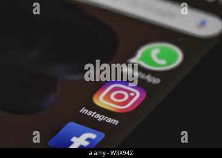 Alicante, Spain- July 6, 2019: Finger pressing Instagram icon on black mobile phone screen. Whatsapp and Facebook icons in the background. Stock Photo