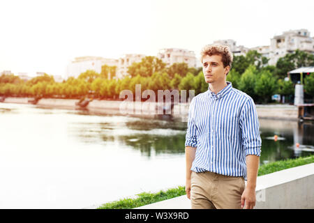 handsome young man walking along river in a european city, traveling or going to work Stock Photo