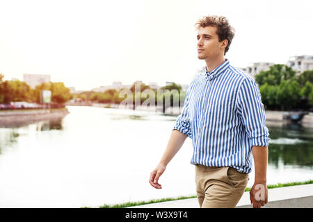 handsome young man walking along river in a european city, traveling or going to work Stock Photo