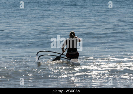 A young woman paddles out into the Coral Sea in her kayak for an early morning exercise from Agnes Water Beach at Agnes Water in Queensland, Australi Stock Photo