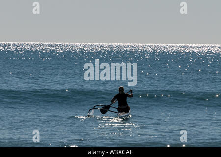 A young woman paddles out into the Coral Sea in her kayak for an early morning exercise from Agnes Water Beach at Agnes Water in Queensland, Australi Stock Photo