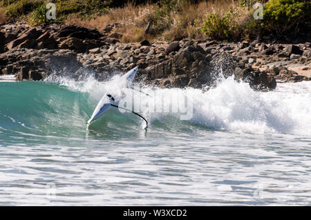 A young Australian woman riding the surf and capsized from her kayak in the Coral Sea at Agnes Water on the Queensland coast in Australia.   Agnes Wat Stock Photo