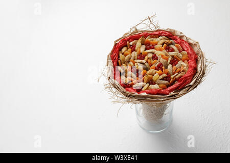 Decorative composition in the form of a bouquet of dried fruits standing in a glass vase on a white table Stock Photo