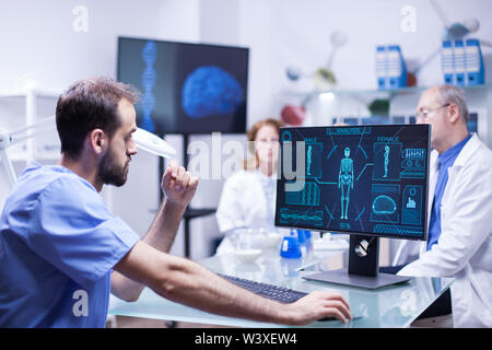 Portrait of young scientist looking at monitor computer checking male body. Team of engineers working in science laboratory. Stock Photo