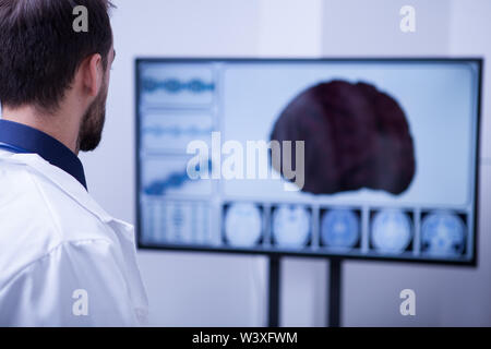 Young male surgeon using technology to check out a patient brain. Brain on the screen. Stock Photo