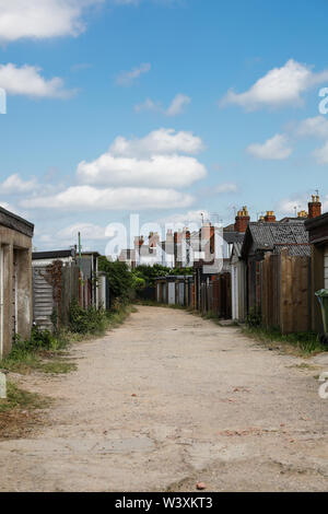 A back street view of the rear of a row of small Victorian terraced houses with garages Stock Photo