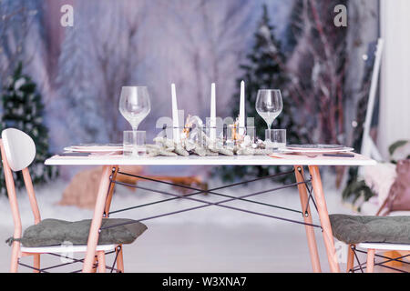 table with Christmas decor reserved for dinner on the background of New Year's wallpaper Stock Photo