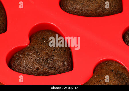 Chocolate sponge cake hearts in red silicone mold. Valentine sweet Stock Photo