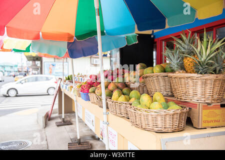 Vendors sell colorful tropical fruit from an outdoor market stall on the main street of Kapaa, Kauai, Hawaii, USA. Stock Photo