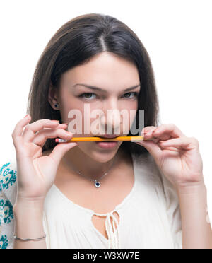 Young woman holding a pencil in her teeth on white background. Stock Photo