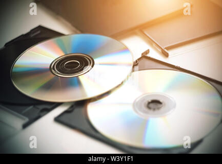 Two CDs for music, video and recording information, which are now less and less used out of use, lie on a white table, illuminated by sunlight. Stock Photo
