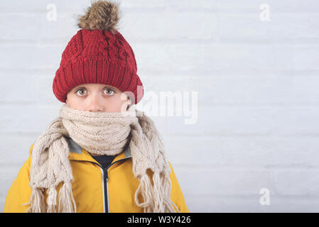 funny child with winter hat and scarf against brick background Stock Photo