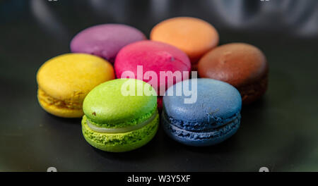 Macarons pastel colors with chocolate cream on black background, close up view with details Stock Photo