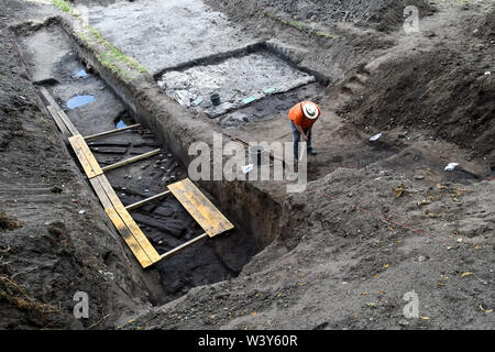 18 July 2019, Saxony-Anhalt, Kemberg: Lous Daniel Nebelsick, professor of archaeology and excavation director, uses a pickaxe to uncover the charred remains of a wall. The excavation is a German-Polish project between the University of Warsaw and the State Office for Monument Preservation in Saxony-Anhalt. The students dig at the late Bronze Age Early Iron Age castle wall of Kemberg, where one of the most important prehistoric castles in Central Germany once stood. Photo: Klaus-Dietmar Gabbert/dpa-Zentralbild/ZB Stock Photo