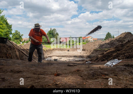 18 July 2019, Saxony-Anhalt, Kemberg: Louis Daniel Nebelsick, professor of archaeology and excavation director, uses a shovel to uncover the charred remains of a wall. The excavation is a German-Polish project between the University of Warsaw and the State Office for Monument Preservation in Saxony-Anhalt. The students dig at the late Bronze Age Early Iron Age castle wall of Kemberg, where one of the most important prehistoric castles in Central Germany once stood. Photo: Klaus-Dietmar Gabbert/dpa-Zentralbild/ZB Stock Photo