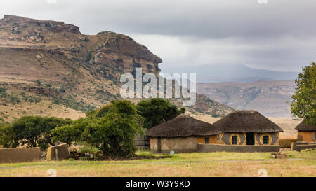 Basotho cultural village traditional thatch round or circular rondawel huts against a mountain in rural national park of Free State in South Africa Stock Photo