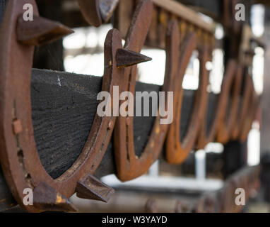 Rusty vintage horseshoes in a row hanging on wooden post Stock Photo