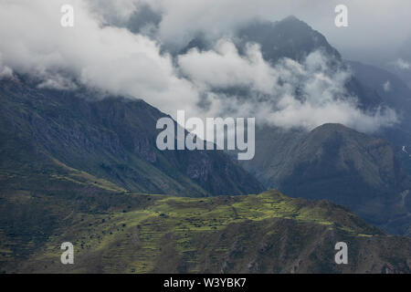 Heavy dramatic clouds over the Peruvian Andes. Somewhere in the Andes near Cuscoю Sunlight paints a small valley in bright green.  Peru. Stock Photo