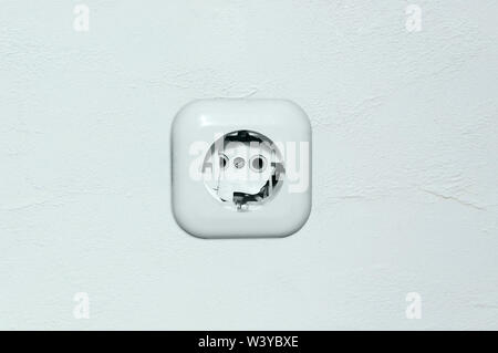 Old broken electrical white socket on the wall. Stock Photo