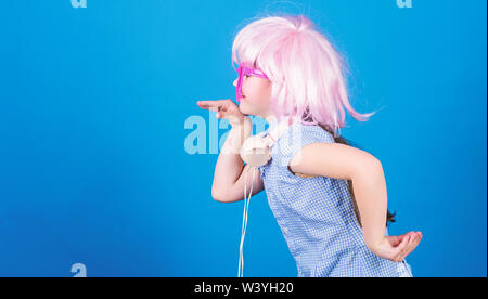 Inspired by music. Little kid listening music. Cute kid with headphones blue background. Small girl headphones pink wig dancing. Child using technology for fun. Modern headphones. Energy motion dance. Stock Photo