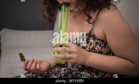 The young person hold in his hand medical marijuana buds and bong. Smoking medical cannabis with bong. Marijuana is a concept of herbal medicine Stock Photo