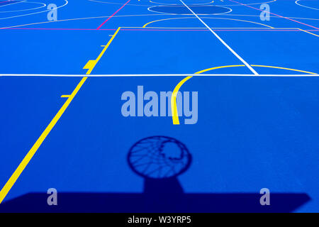 Shadow of a basketball basket on the floor of the court, painted blue and background with lines. Stock Photo