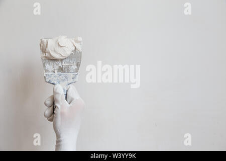 Worker in white gloves performs plastering of the walls of the room Stock Photo