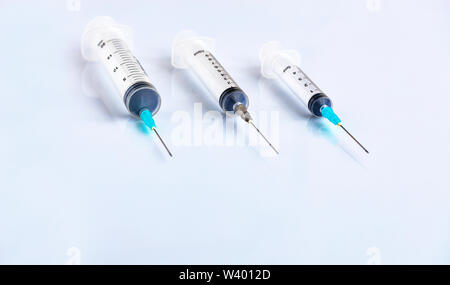 Three syringes of different capacity on a white table, prepared for injection in the hospital with copyspace for text. Stock Photo