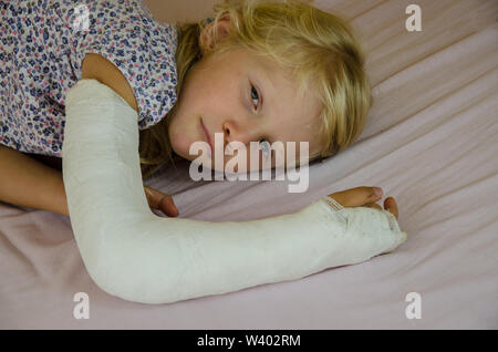 hurt blond girl with broken hand Stock Photo