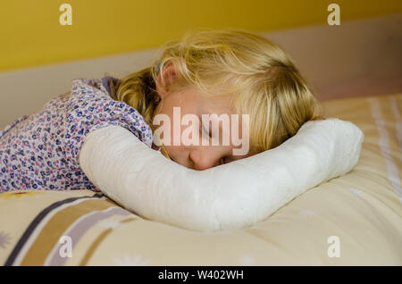 hurt blond girl with broken hand lying in hand Stock Photo