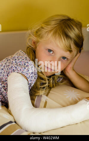 hurt blond girl with broken hand lying on hand Stock Photo