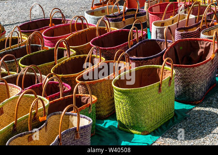 A display of colourful handmade wicker baskets for sale in a French market suitable for carrying shopping Stock Photo