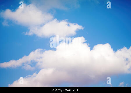 White and gray fluffy clouds against the blue sky during the day in summer weather Stock Photo