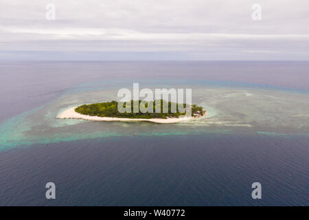 Round tropical island with white sandy beach, top view. Mantigue Island, Philippines.Small inhabited island surrounded by a coral reef. Stock Photo