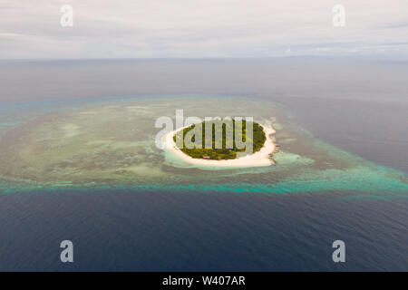 Round tropical island with white sandy beach, top view. Mantigue Island, Philippines.Small inhabited island surrounded by a coral reef. Stock Photo