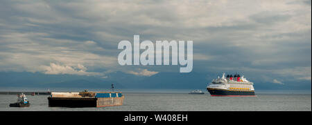 Luxury cruise ship Disney Wonder departing port of Victoria with barge and tugboat in foreground-Victoria, British Columbia, Canada. Stock Photo