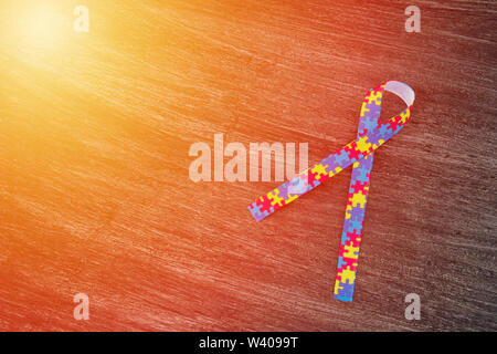 World Autism awareness and pride day or month with Puzzle pattern ribbon on wooden background. Stock Photo