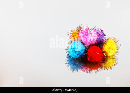 Colored beautiful pompons on a gray background. Assortment of pompons on the mirror surface. Stock Photo