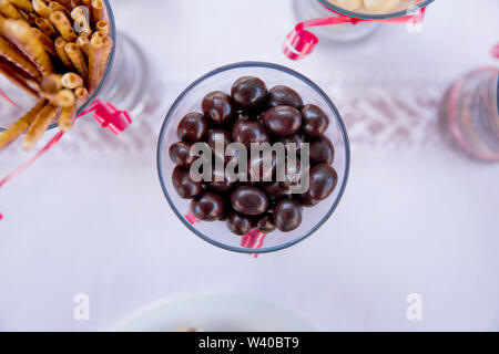 Dark chocolate candy balls in a glass bowl on white background, isolated . Dark chocolate balls with almond heart. in a glass jar .In a round black ch Stock Photo