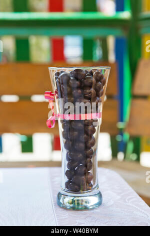 Dark chocolate candy balls in a glass bowl on white background, isolated . Dark chocolate balls with almond heart. in a glass jar .In a round black ch Stock Photo