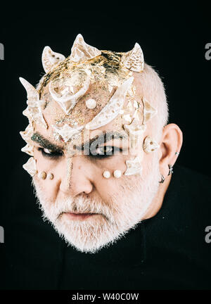 Stern demon face with evil look isolated on black background. Monster with thorns and golden dragon skin. Mythical creature, magical beast, fairy tale Stock Photo