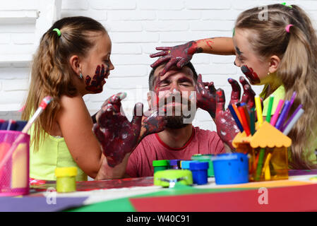 Girls drawing on man face skin with colorful paints Stock Photo