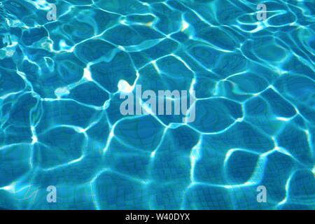 Abstract patterns formed by strong sunlight on the surface of water in a swimming pool  similar to  David Hockney's famous paintings Stock Photo