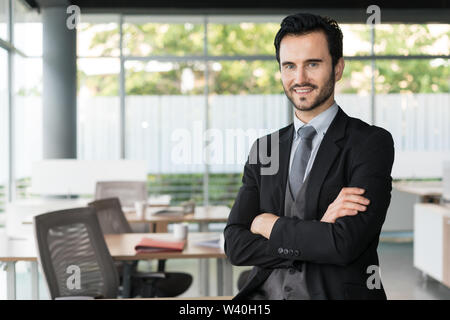 Happy business man standing with arms crossed at office. Stock Photo