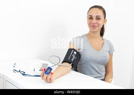 young smiling beautiful girl measures the pulse and blood pressure at the reception of a therapist. Stock Photo